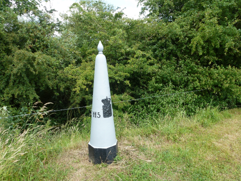 Grenspaal langs de Maas.